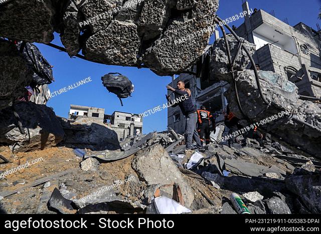 19 December 2023, Palestinian Territories, Rafah: Members of the civil defence teams carry out search and rescue operations in the rubble of a residential...