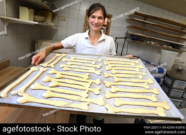 08 January 2020, Bavaria, Irsee: Gudrun Koneberg, master baker, holds a baking tray with lye pastries in the shape of a bone in the bakery of her bakery
