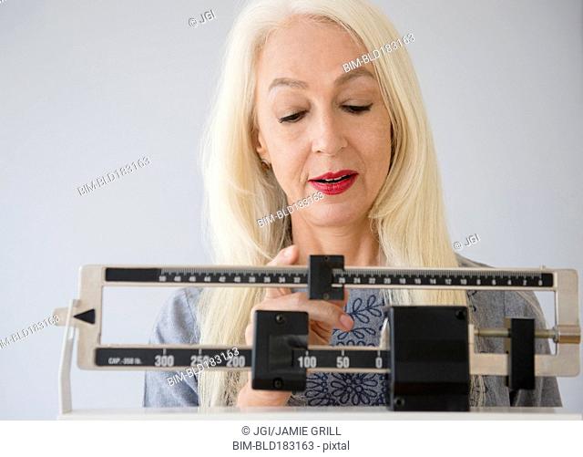 Caucasian woman weighing herself on scale