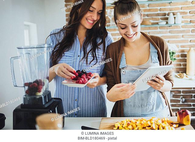 Caucasian women using digital tablet in kitchen