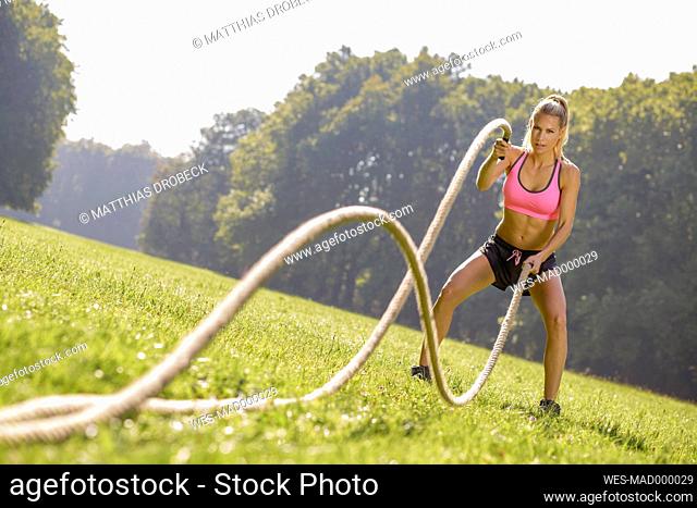 Young woman training with workout ropes on a meadow
