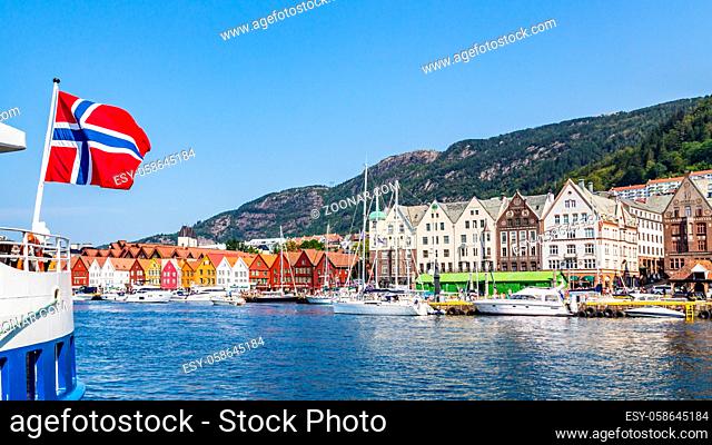 Bergen, Norway, Scandinavia - July 30, 2019: Norwegian flag with the port of Bergen and view on the historical buildings of Bryggen in Bergen, Norway