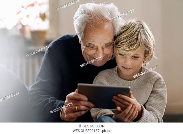 Grandfather and grandson using a tablet at home