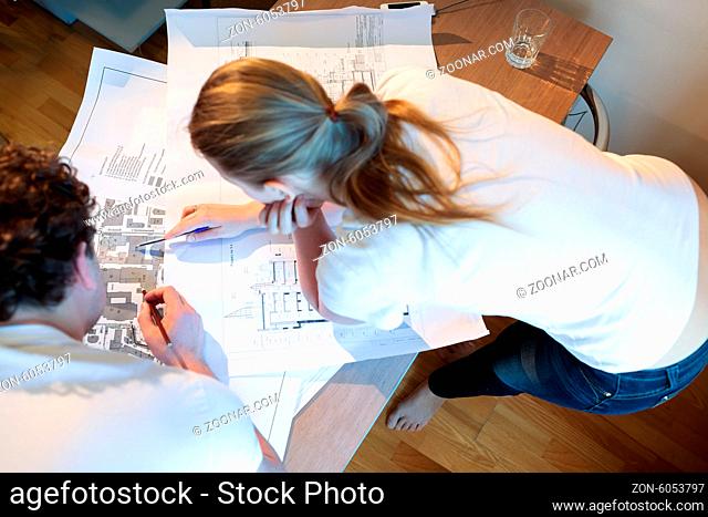 High angle shot of male and female architects at work. Woman pointing on the place on the map
