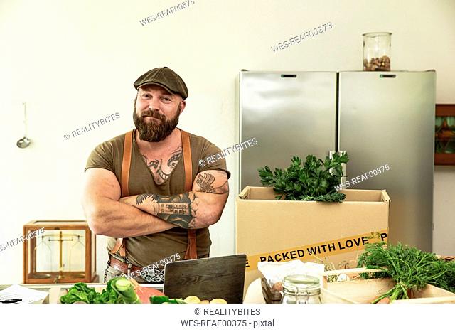 Owner of a delivery service for organic vegetables, standing proud in his kitchen