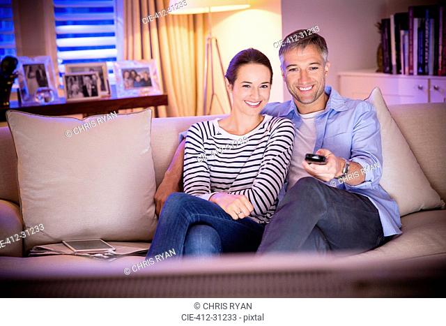 Smiling couple watching TV in living room