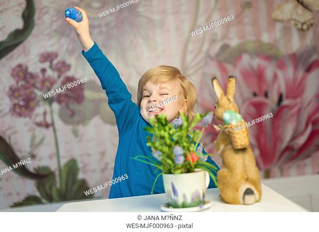 Happy blond boy with Easter bunny holding egg