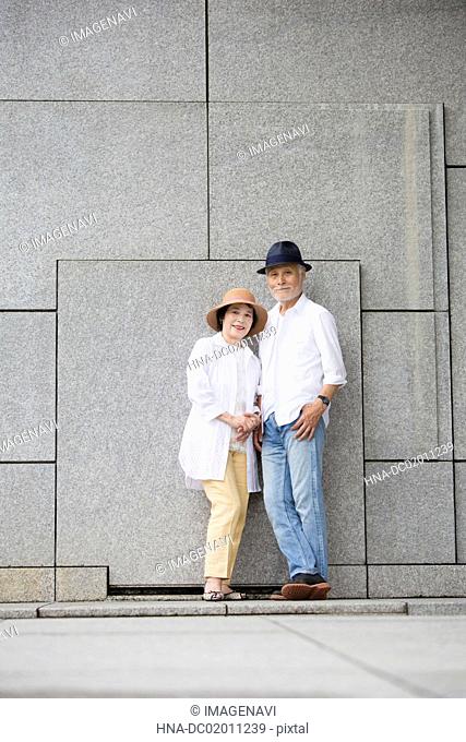 Senior couple standing against wall