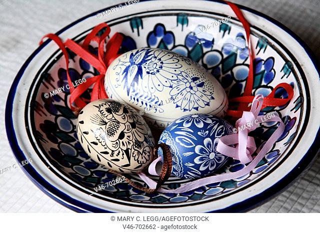 Three handpainted traditional Czech Easter eggs rest in a handpainted ceramic bowl with blue motif. two small eggs with traditional onion style motifs rest with...