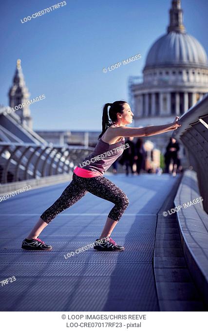 A woman resting on the Millennium Bridge after a run with St Paul's Cathedral in the background