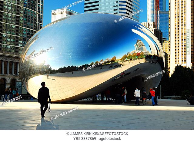 A small group of tourists gather around The Bean, a popular sculpture in downtown Chicago