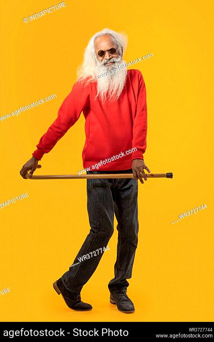 A CHEERFUL OLD MAN HAPPILY POSING WITH WALKING STICK