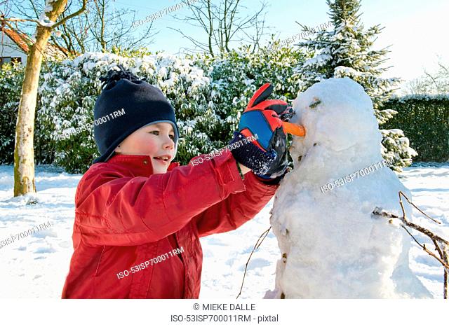 Boy making snowman in garden