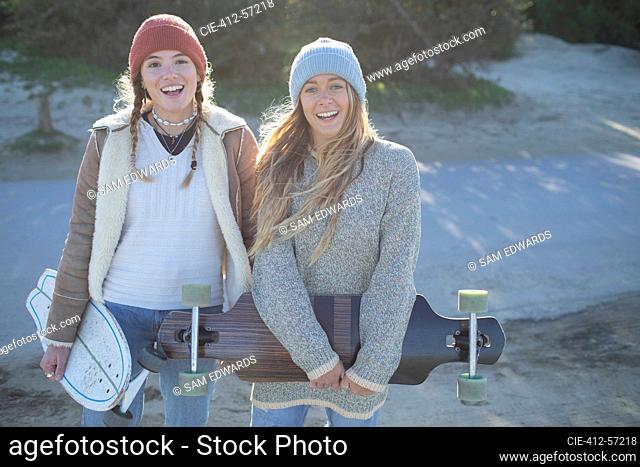 Portrait happy young women friends in knit hats with skateboards