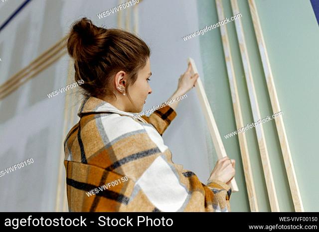 Young woman working with wooden stick in apartment