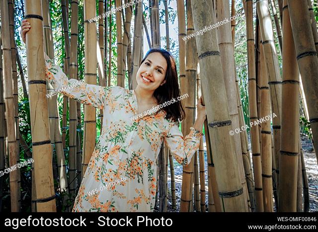 Smiling young woman standing in bamboo grove