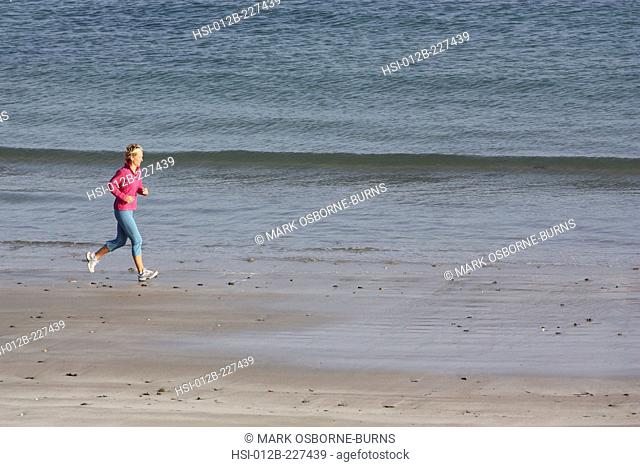 Blonde woman outdoors. Jogging along beach