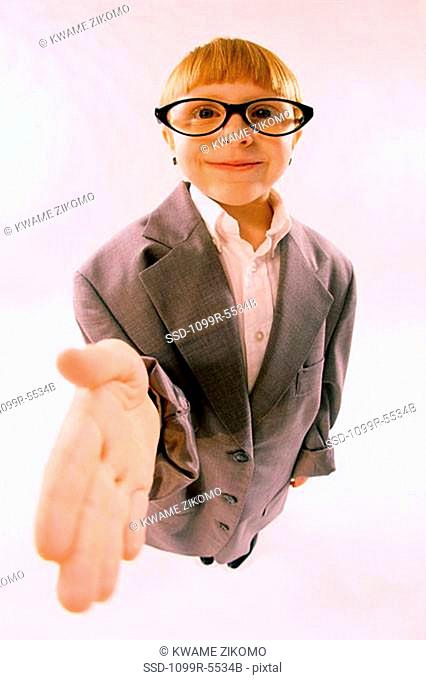 Portrait of a young boy dressed as a businessman holding his hand out smiling