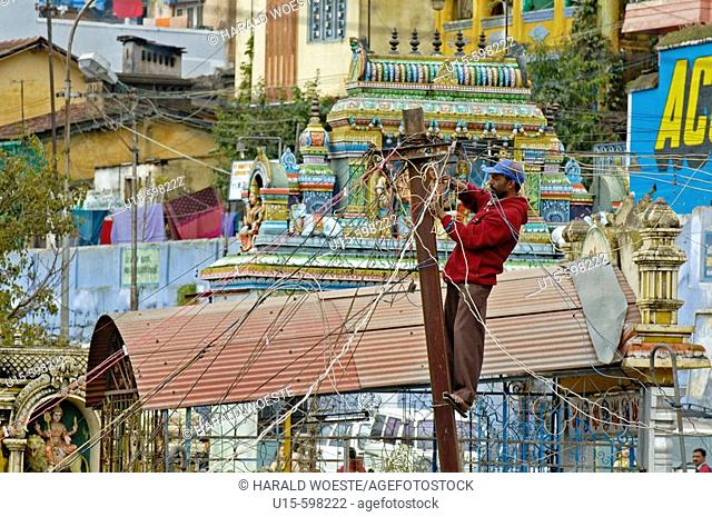 India. Tamil Nadu. Coonoor. Indian electrician working on wiring post in Coonoor
