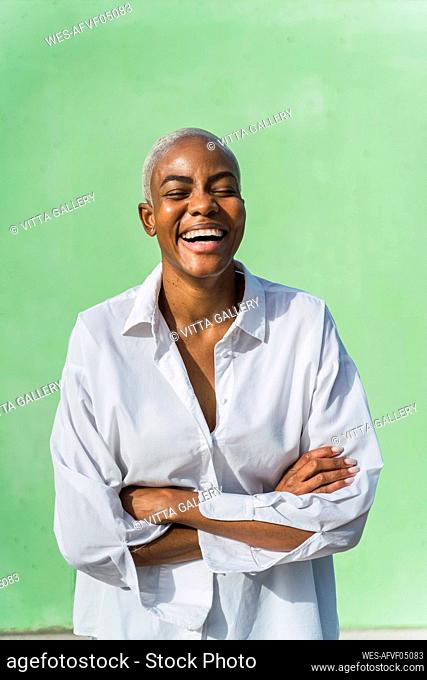 Portrait of laughing woman in front of green wall