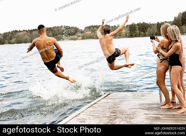 People jumping into lake from jetty