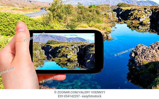 travel concept - tourist photographs Silfra fissure in rift valley of Thingvellir national park in Iceland in september on smartphone