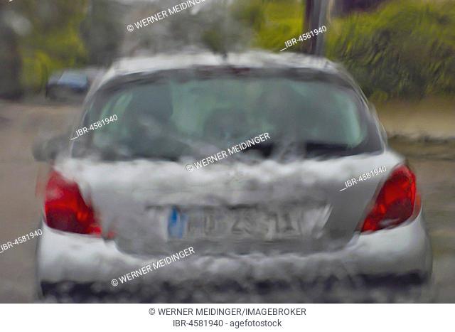 Cloudburst, driving in heavy rain, view through windshield to driving ahead car, Germany