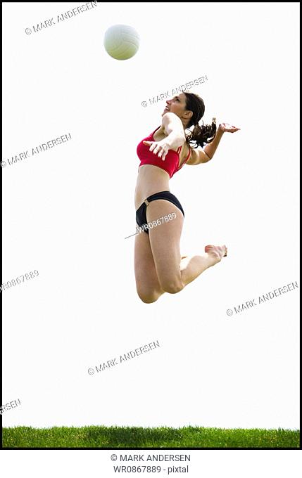 Woman jumping and spiking volleyball outdoors