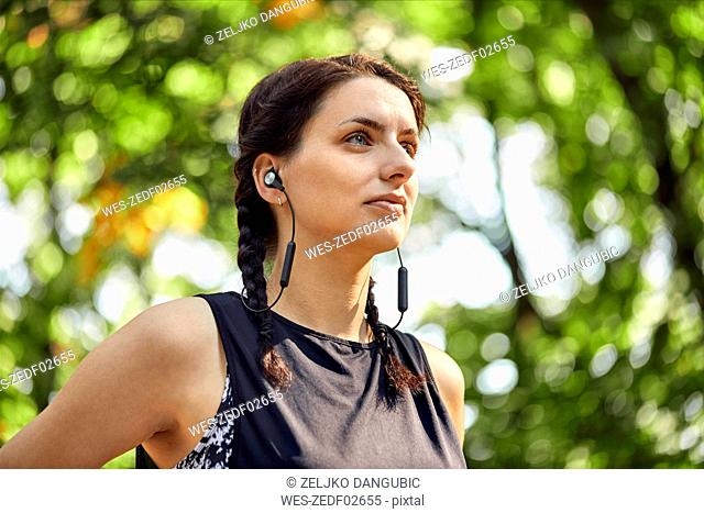 Portrait of sporty young woman with earphones in forest