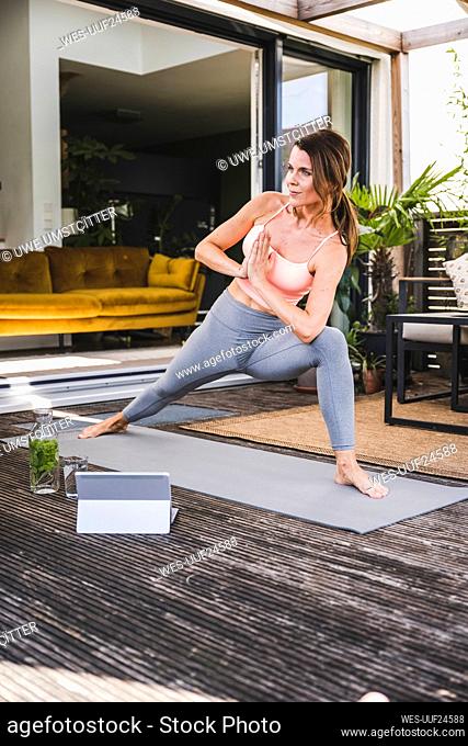 Woman practicing yoga pose on exercise mat on terrace