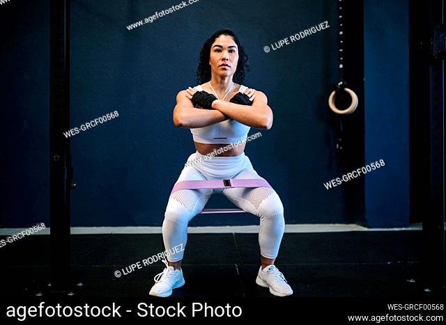 Sportswoman with resistance band in gym against wall