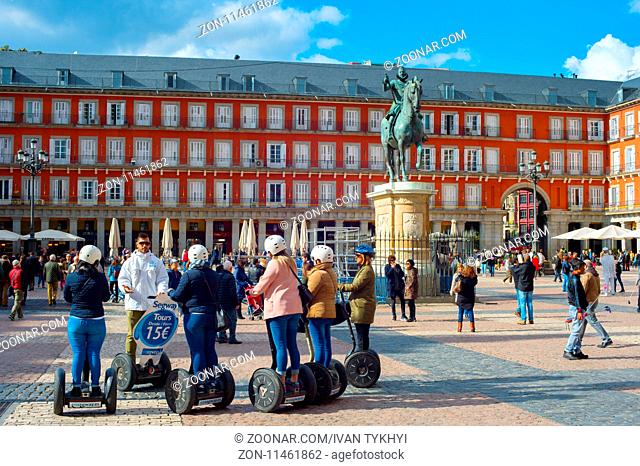 MADRID, SPAIN - NOV 07, 2016: Group of tourist on Segway on a Mayor Plaza in front of the statue of King Philips III in Madrid