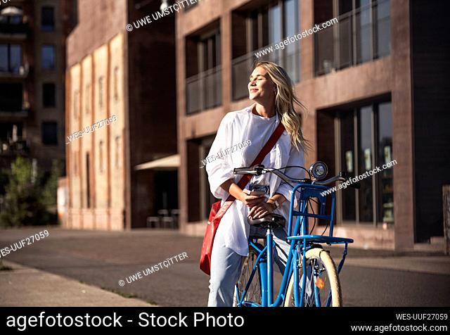Smiling woman enjoying sunlight sitting on bicycle
