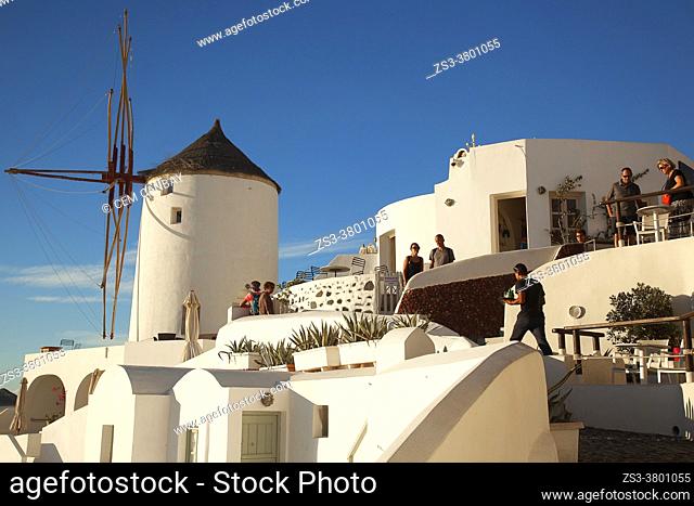 Tourists near the traditional windmill and whitewashed houses in Oia village, Santorini Island, Cyclades Islands, Greek Islands, Greece, Europe