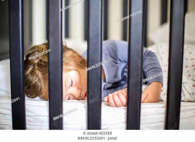 Caucasian baby girl sleeping in crib