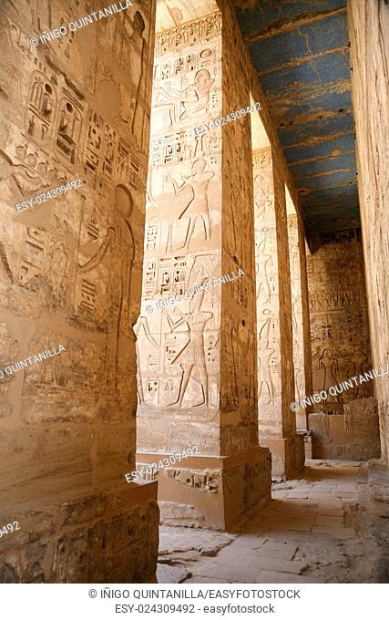 Egyptian paintings, carving figures and hieroglyphs in columns and wall of landmark Temple of Ramses or Ramesses III at Medinet Habu, monument in Luxor, Egypt