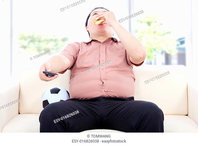 fat business man drinking beer and sitting on sofa to watch TV