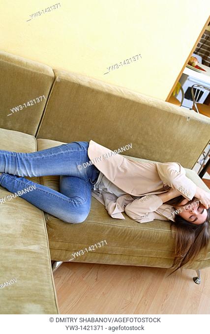 Young woman in jeans sleeping on sofa