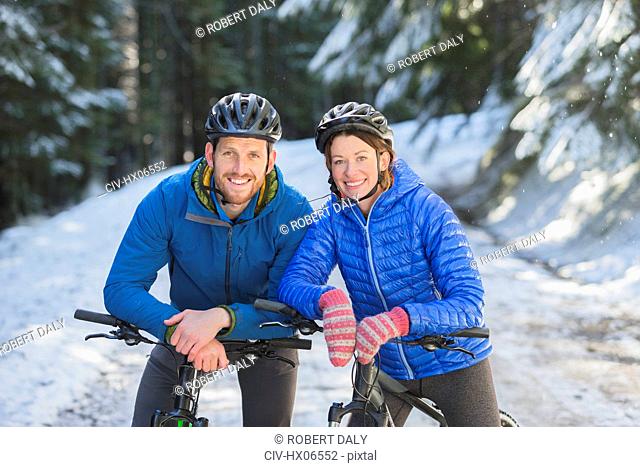 Happy couple mountain biking in snow