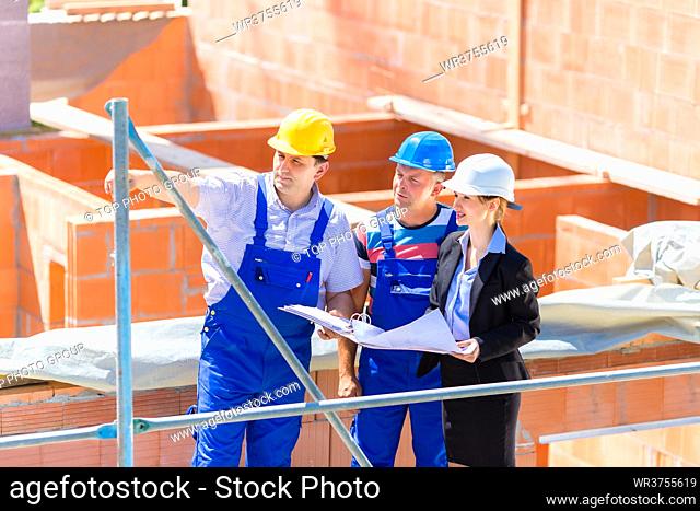 Construction site Team or architect and builder or worker with helmets discuss on a scaffold construction plan or blueprint or checklist