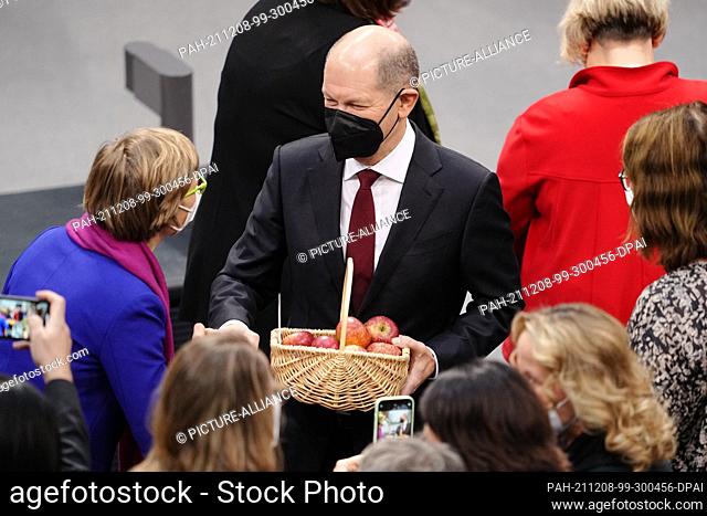 08 December 2021, Berlin: Members of parliament congratulate Olaf Scholz (M , SPD) after his election as Federal Chancellor , holding a basket of apples