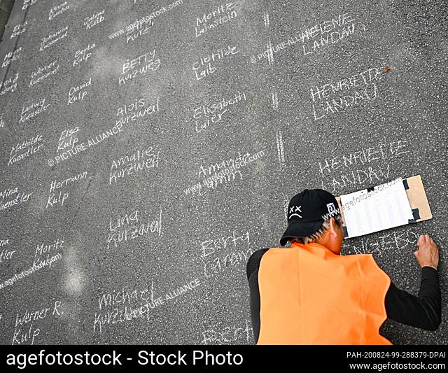 24 August 2020, Hessen, Frankfurt/Main: Alejandro Streinesberger from Frankfurt writes names on the street with white school chalk at the art action ""Writing...