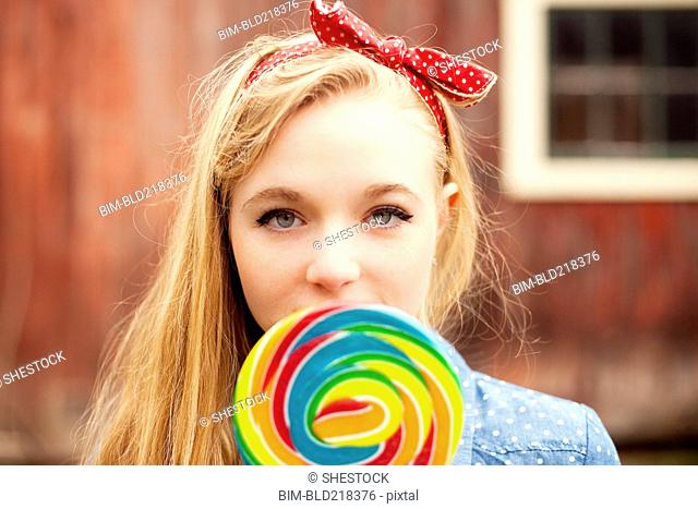 Caucasian teenage girl licking lollipop