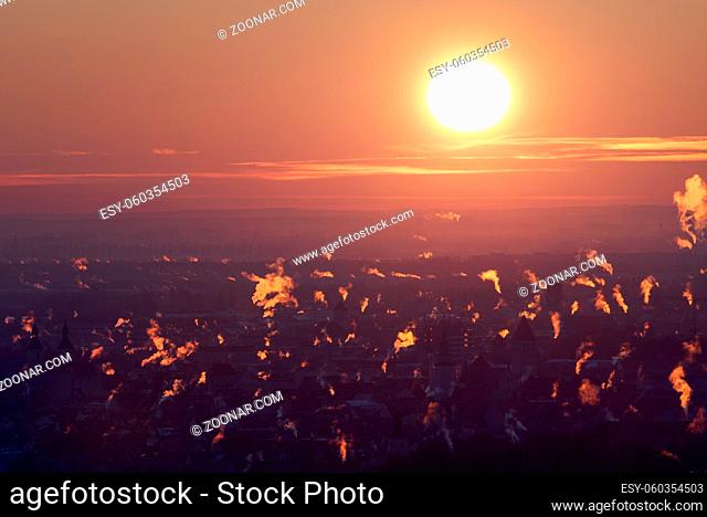 Overview of city skyline at the beginning of the heating period in autumn with many smoking chimneys in morning backlight twilight in Regensburg, Bavaria