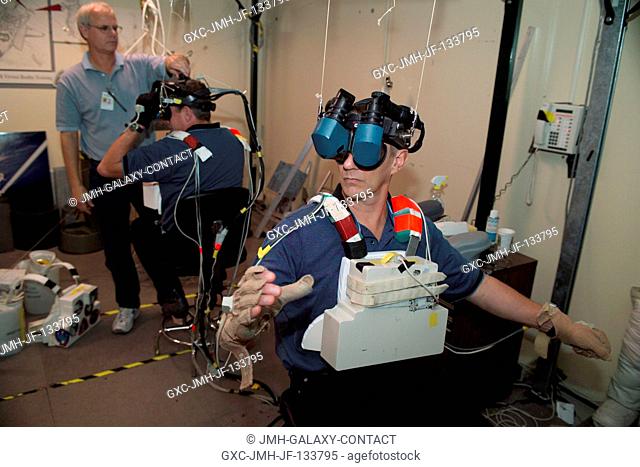 Astronauts Piers J. Sellers (foreground) and Michael E. Fossum, both STS-121 mission specialists, use virtual reality hardware in the Space Vehicle Mockup...