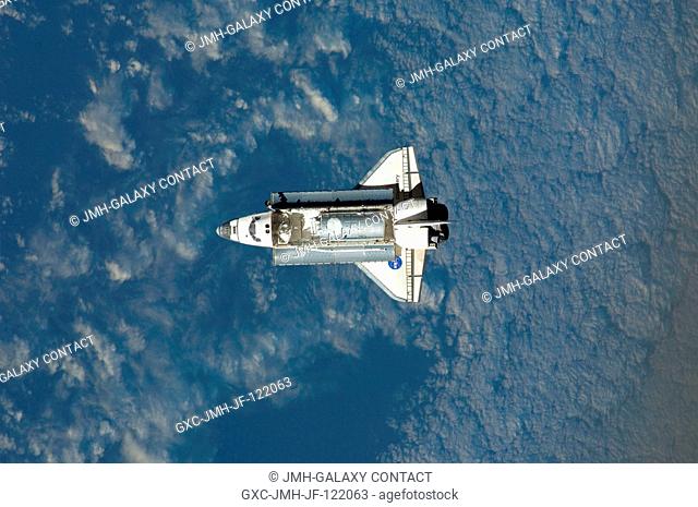 Backdropped by a cloud-covered part of Earth, Space Shuttle Discovery approaches the International Space Station during STS-124 rendezvous and docking...
