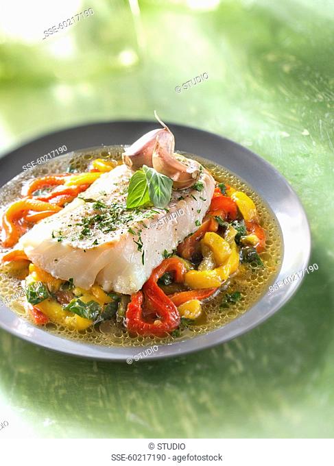 Piece of cod with pink garlic and tarragon on a bed of warm bell pepper salad