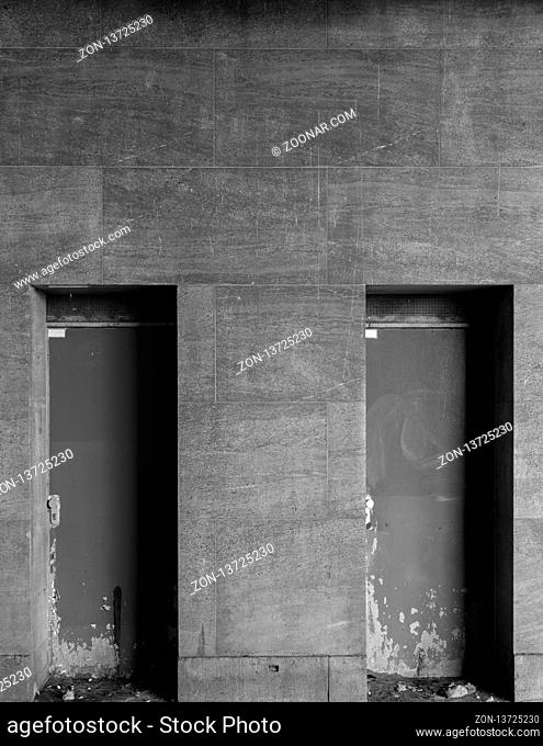 Two different paths behind the gray wall in black and white