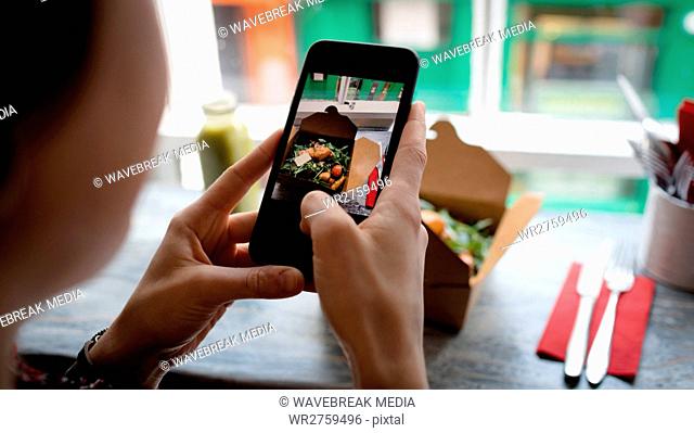Woman clicking a photo of salad from mobile phone