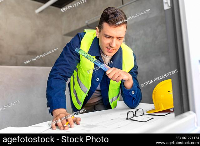 male architect with blueprint and ruler at office